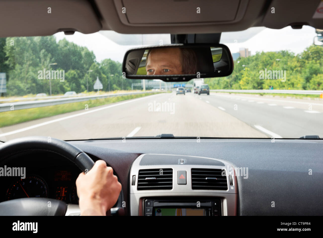 Man, driving a car, with his eyes reflected in the rear view mirror