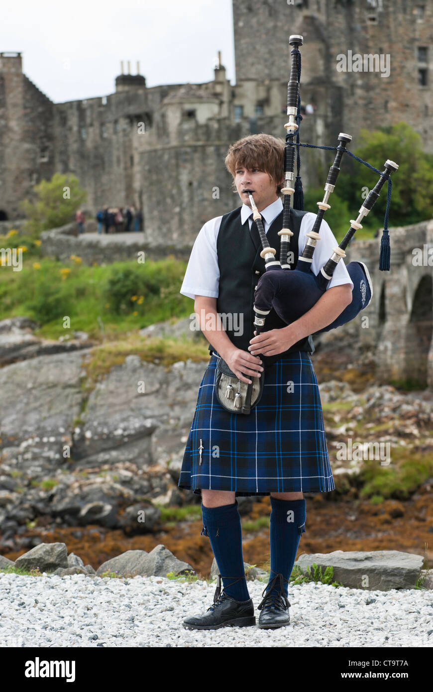 Scotsman wearing traditional cloths while playing the bagpipe at Eilean Donan Castle Scotland UK. Stock Photo
