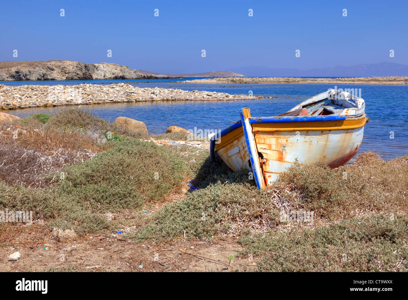 secluded bay with an old boat on Delos, Greece Stock Photo