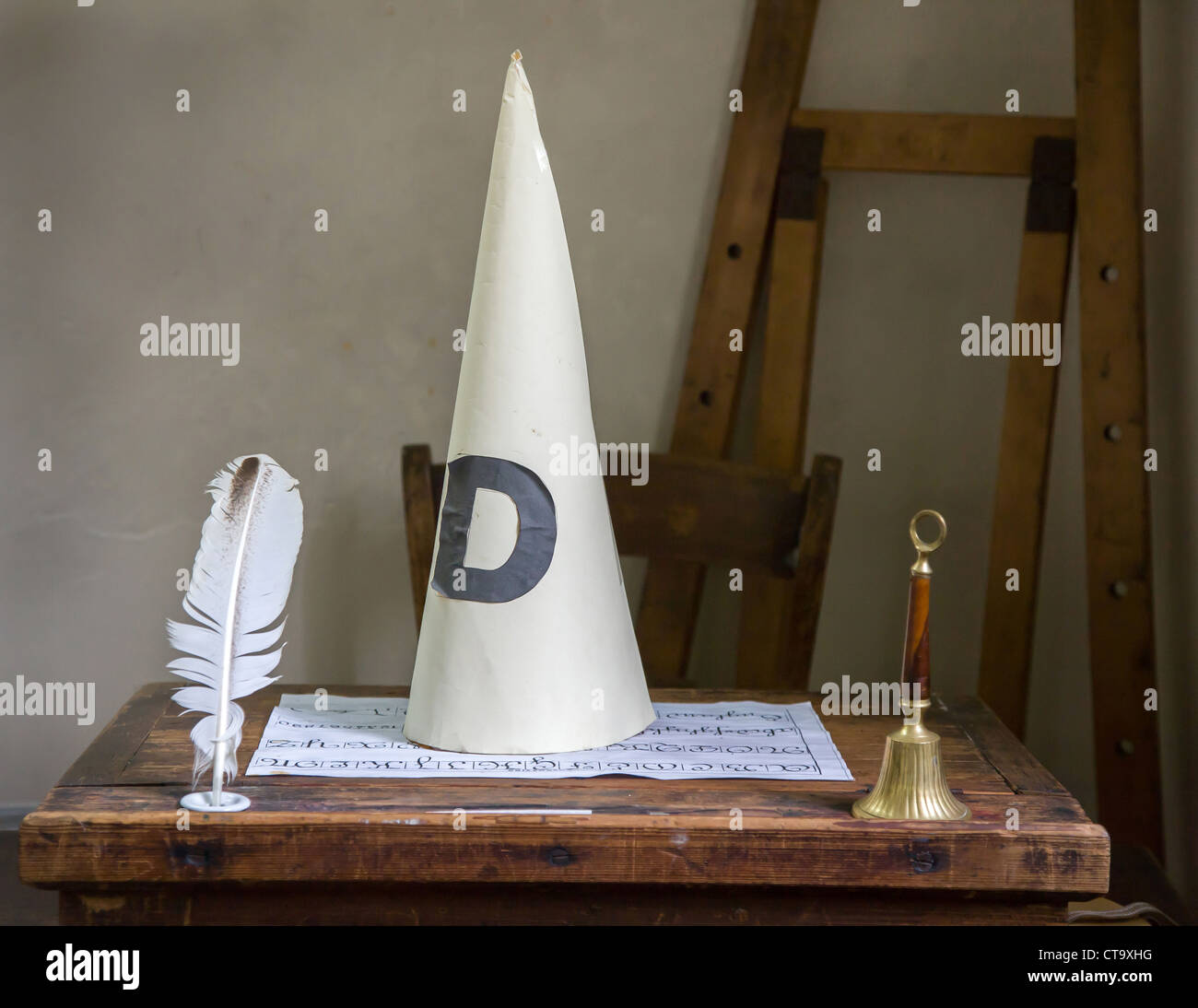 Dunces cap bell and writing quill on a school desk Stock Photo