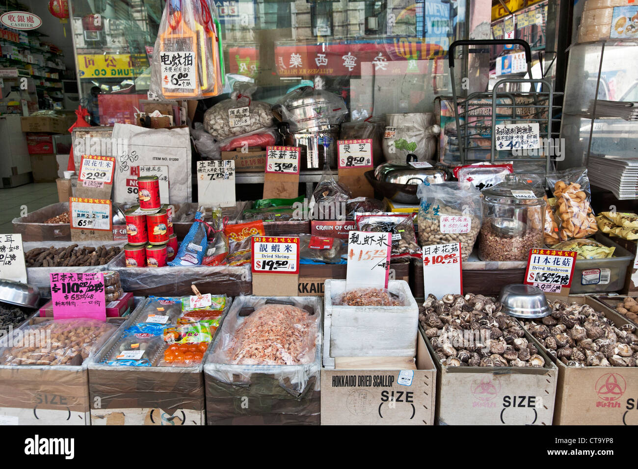 dried seafood legumes & other food items displayed with cookware on sidewalk outside Chinese corner grocery in Chinatown NYC Stock Photo