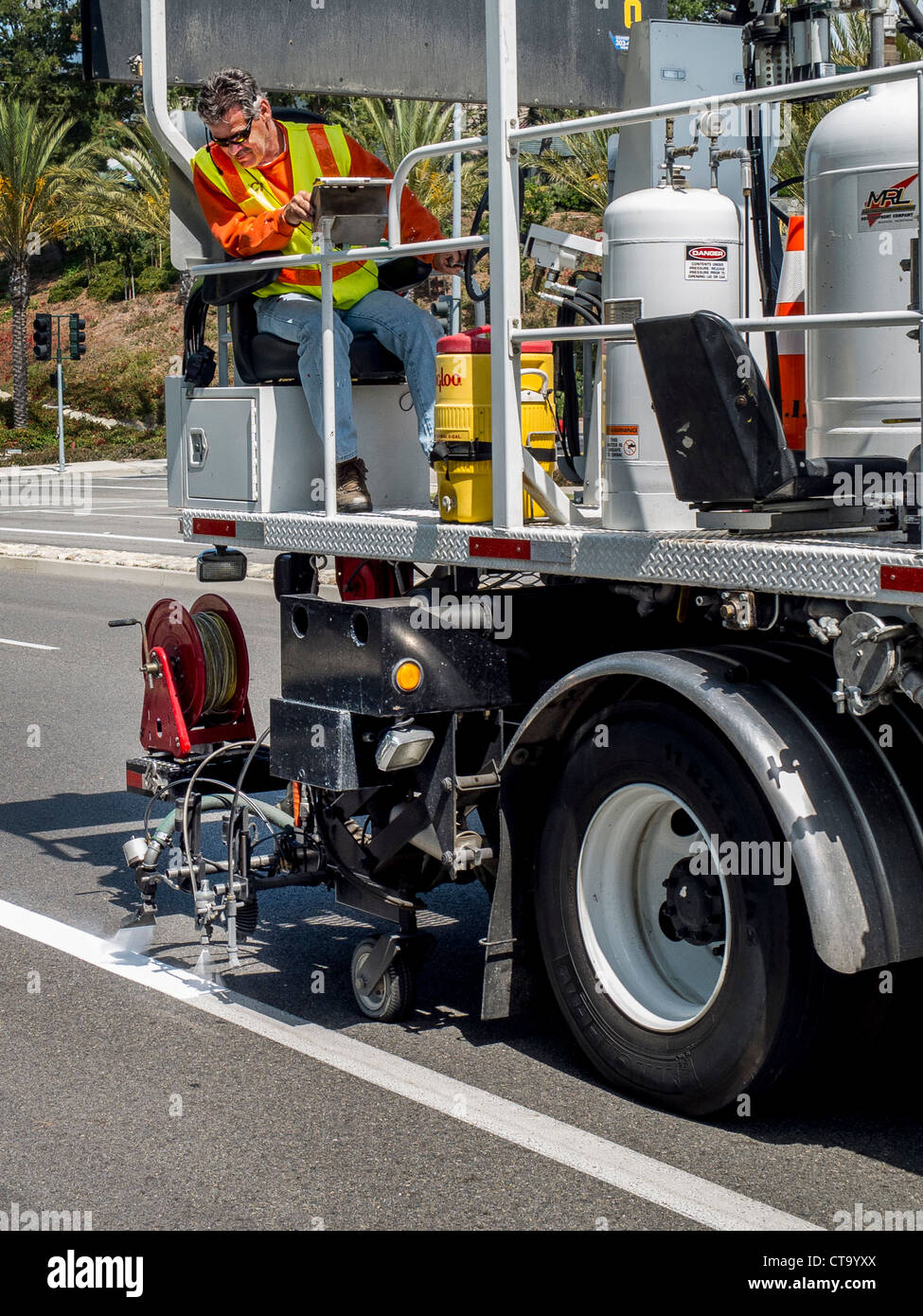 Road striping paint is reapplied to traffic lanes on a street in Laguna