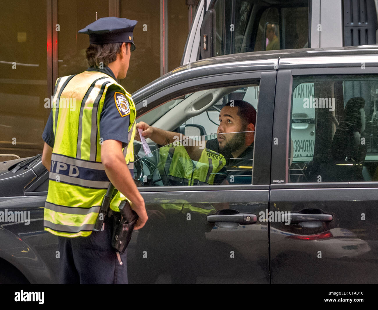 A driver asks directions from a policeman in Times Square, New York City. Stock Photo