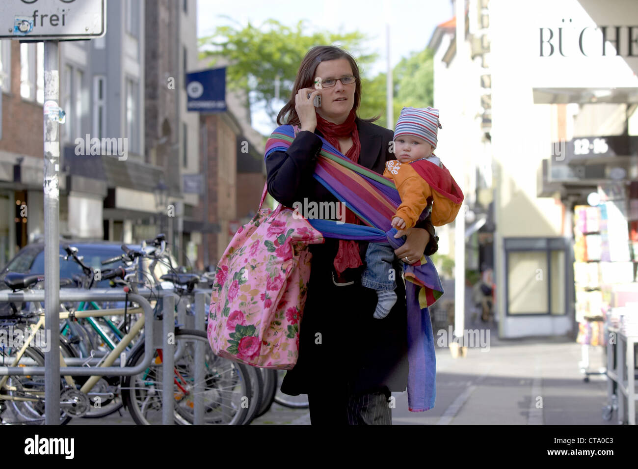 Berufstaetige mother with baby in the street Stock Photo