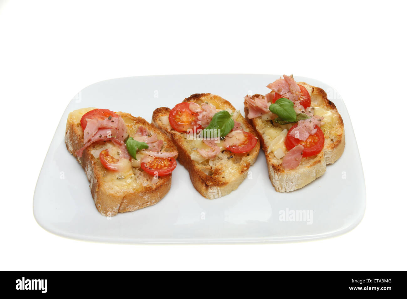 Toasted savory snack, cheese,ham, tomato and basil on ciabata bread on a plate isolated against white Stock Photo