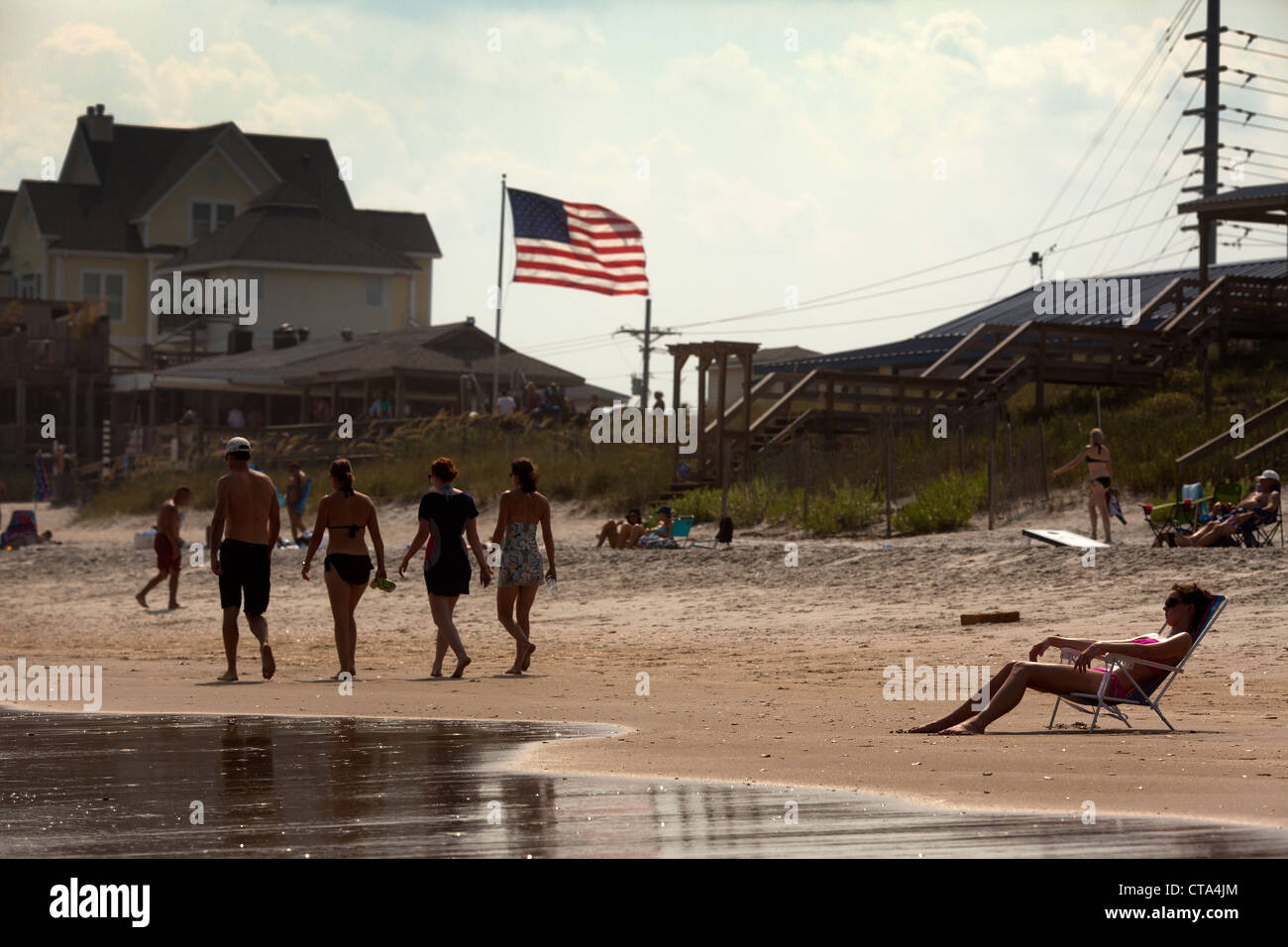 Tourists sunbathing  on Surf City beach , Topsail Island , North Carolina , USA with stars and stripes American flag  summer sun Stock Photo