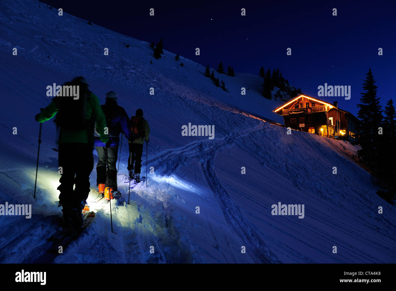 Three men backcountry skiing at night reaching hut Staufner Haus, Hochgrat, Nagelfluh range, Allgaeuer Alpen range, Allgaeu, Bav Stock Photo