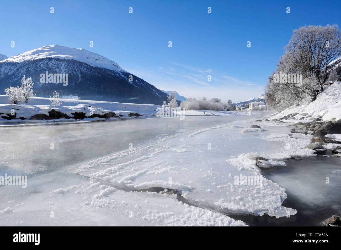 River Inn with ice-covered bank and La Punt-Chamues-ch in background, La Punt, Upper Engadin, Engadin, Grisons, Switzerland, Eur Stock Photo