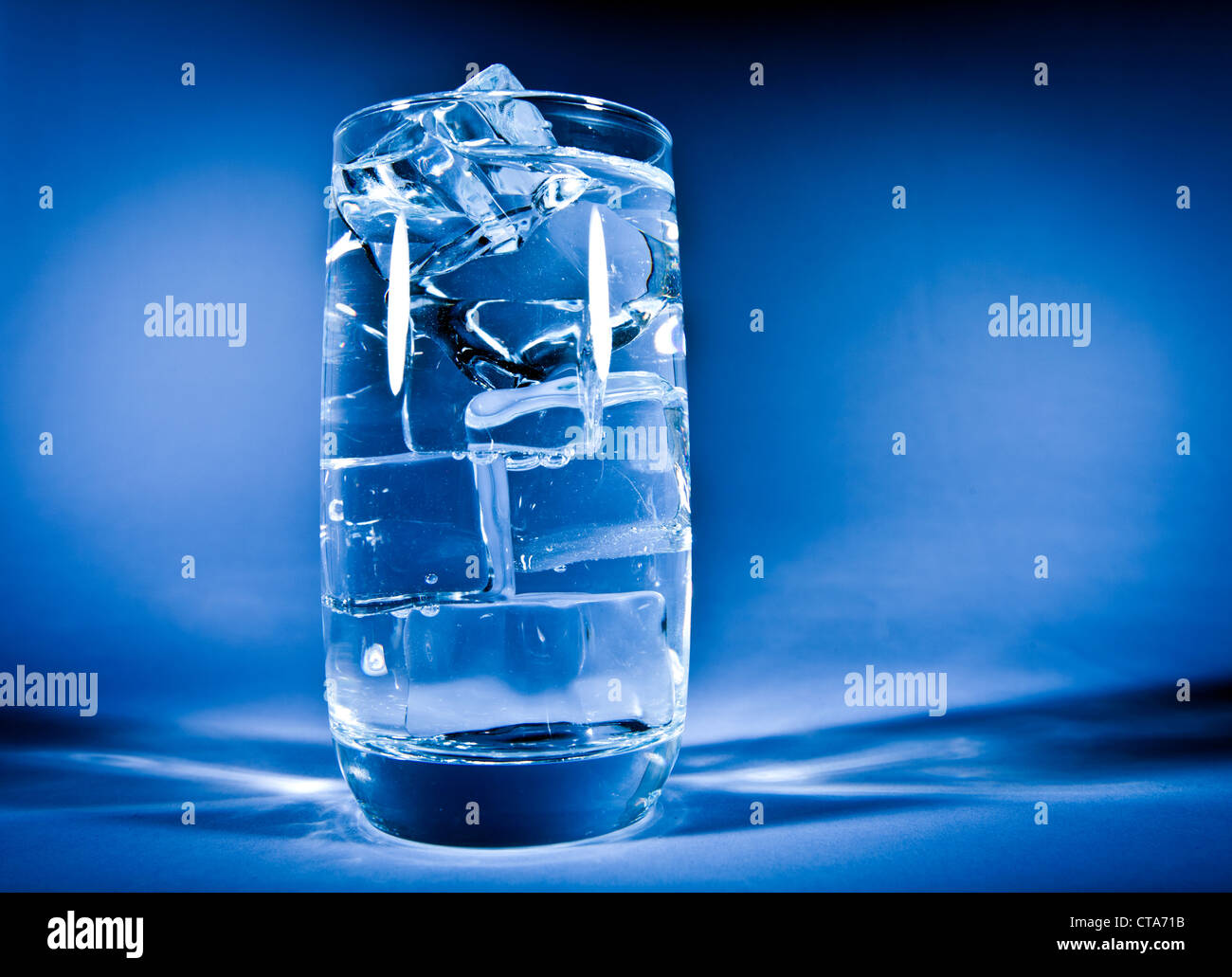 Glass of water with ice on a dark blue background Stock Photo - Alamy