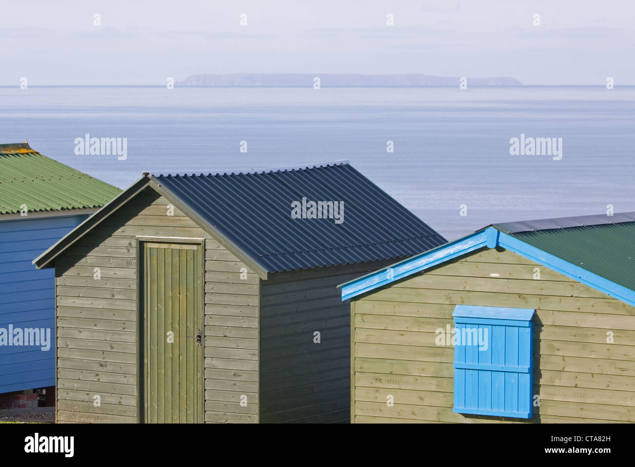 A line of traditional wooden holiday chalets on a cliff in North Devon in winter overlooking