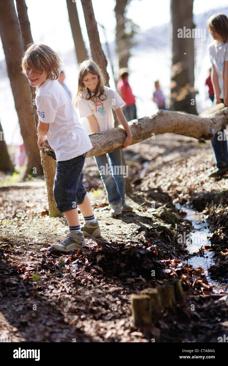 Children playing along the lakeshore, jumping over a stream, Leoni castle grounds, Leoni, Berg, Lake Starnberg, Bavaria, Germany Stock Photo