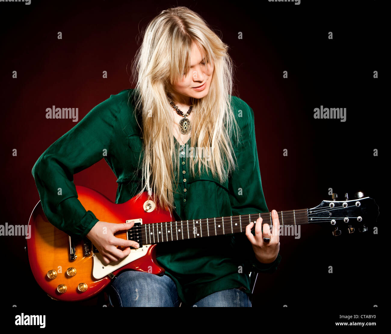 girl with a guitar on a dark red background Stock Photo - Alamy