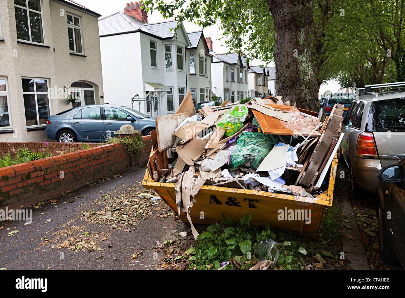 Overflowing skip in residential street, Cardiff, Wales, UK Stock Photo