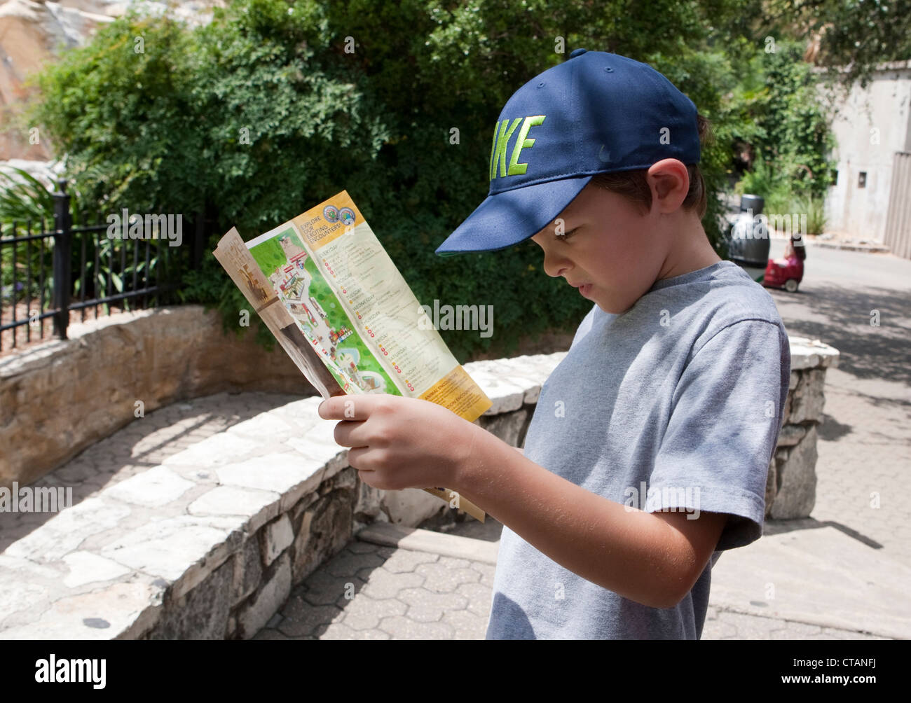 7 year old Mexican-American boy reads brochure and looks at map of San Antonio Zoo in Texas. Stock Photo