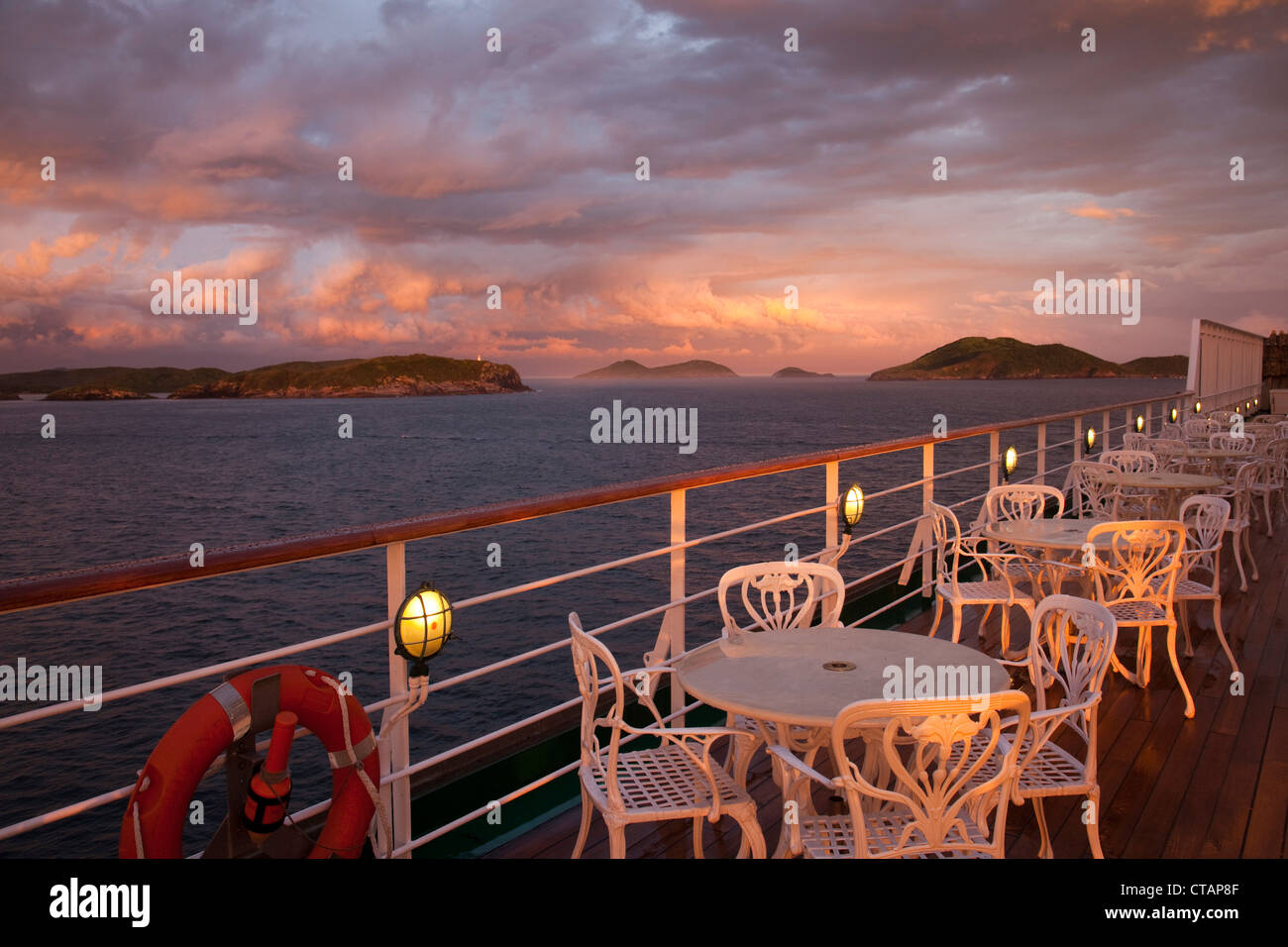Tables and chairs on deck of cruise ship MS Deutschland, Reederei Peter Deilmann, with storm clouds at sunset, Cabo Frio, Rio de Stock Photo