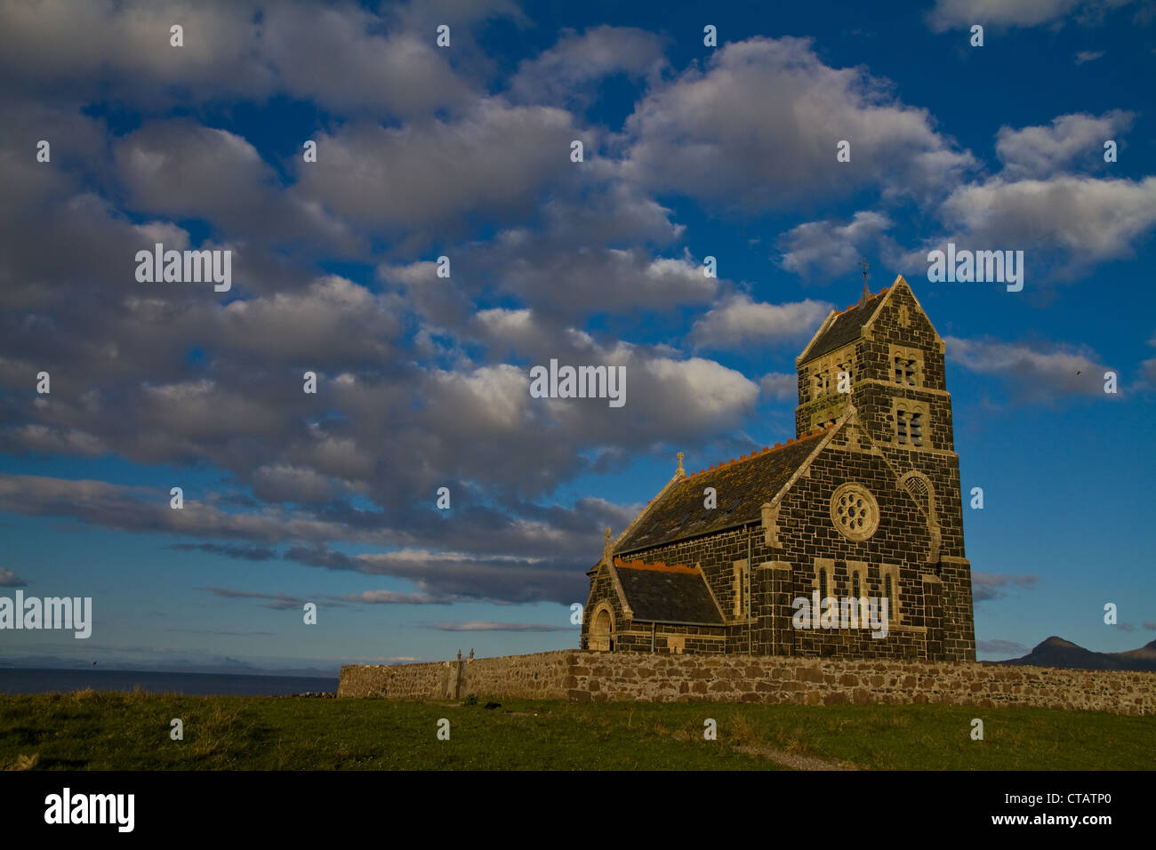 St Edward's Church on Sanday, Isle of Canna, Small Isles, Scotland, against a bright blue sky and white clouds Stock Photo