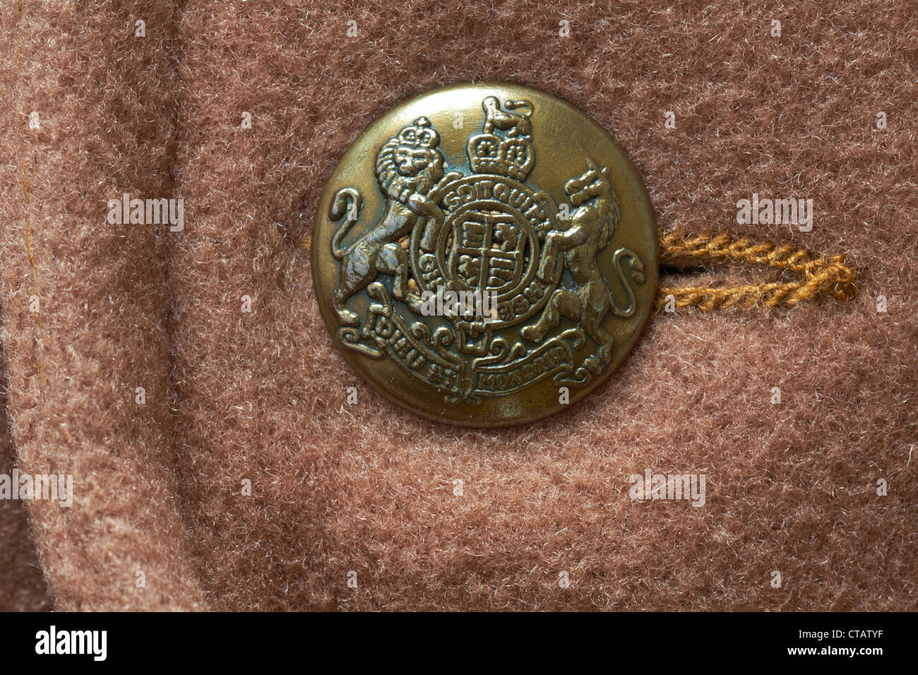 decorative gold coloured button with Dieu et mon droit motto and shield of the coat of arms of the UK on Daniel Hechter brown woolen coat Stock Photo