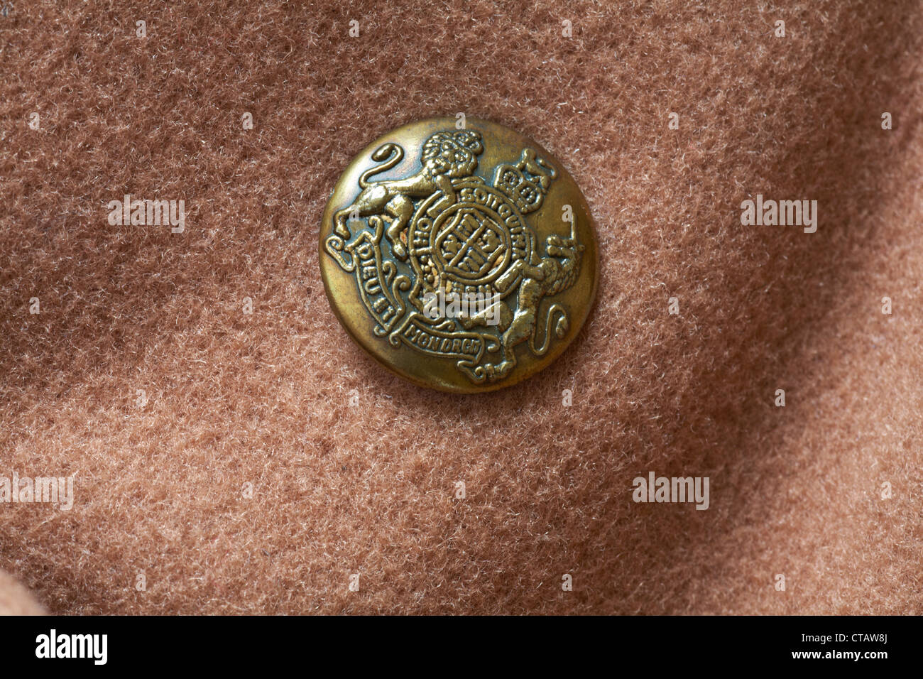 decorative gold coloured button with Dieu et mon droit motto and shield of the coat of arms of the UK on Daniel Hechter brown woolen coat Stock Photo