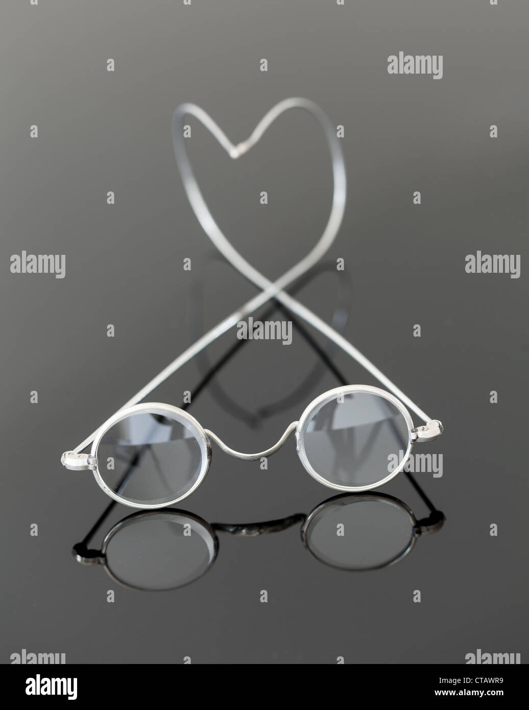 Pair of old silver framed magnifying glasses reflecting on black surface Stock Photo