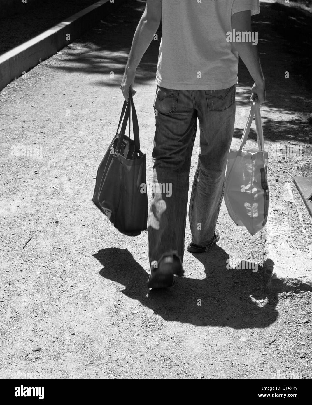 A man carries 2 bags as he walks home through a park Stock Photo Alamy