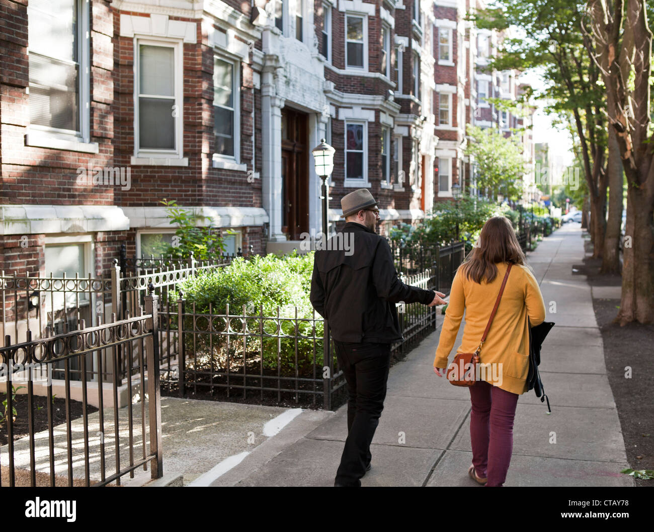 2 people converse as they walk in front of an apartment building in Boston. Stock Photo