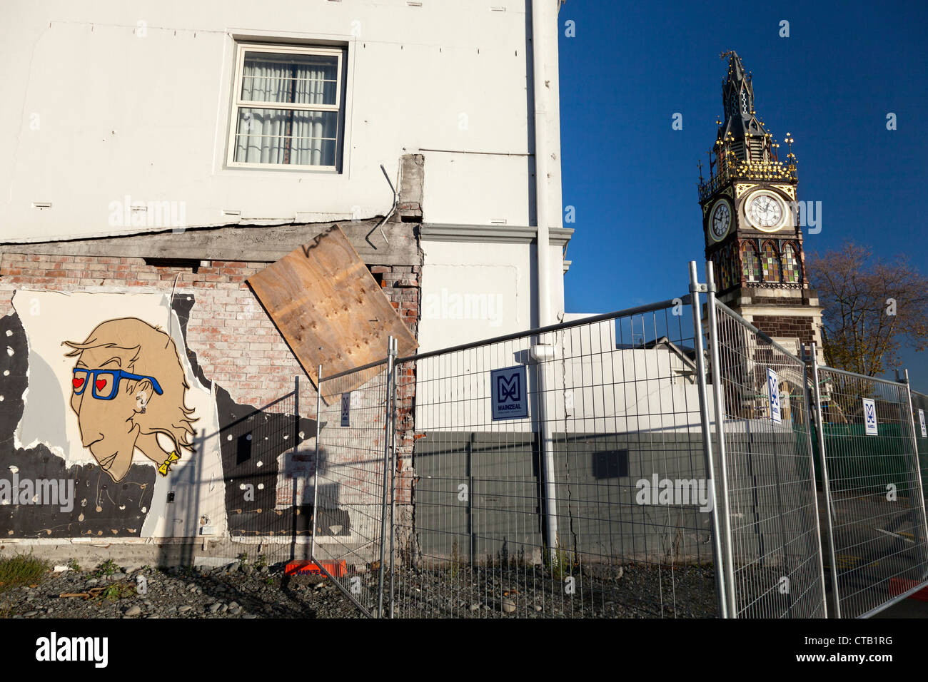 Post-quake Christchurch, New Zealand - fence to the Red Zone, and damaged clock tower Stock Photo