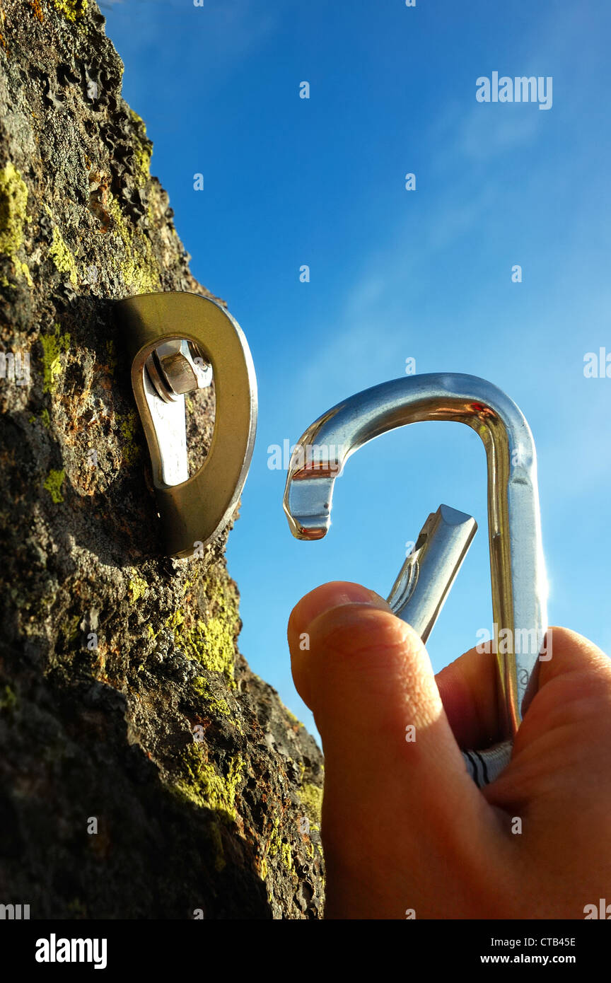 Hand attaching carabiner to a rock anchors Stock Photo