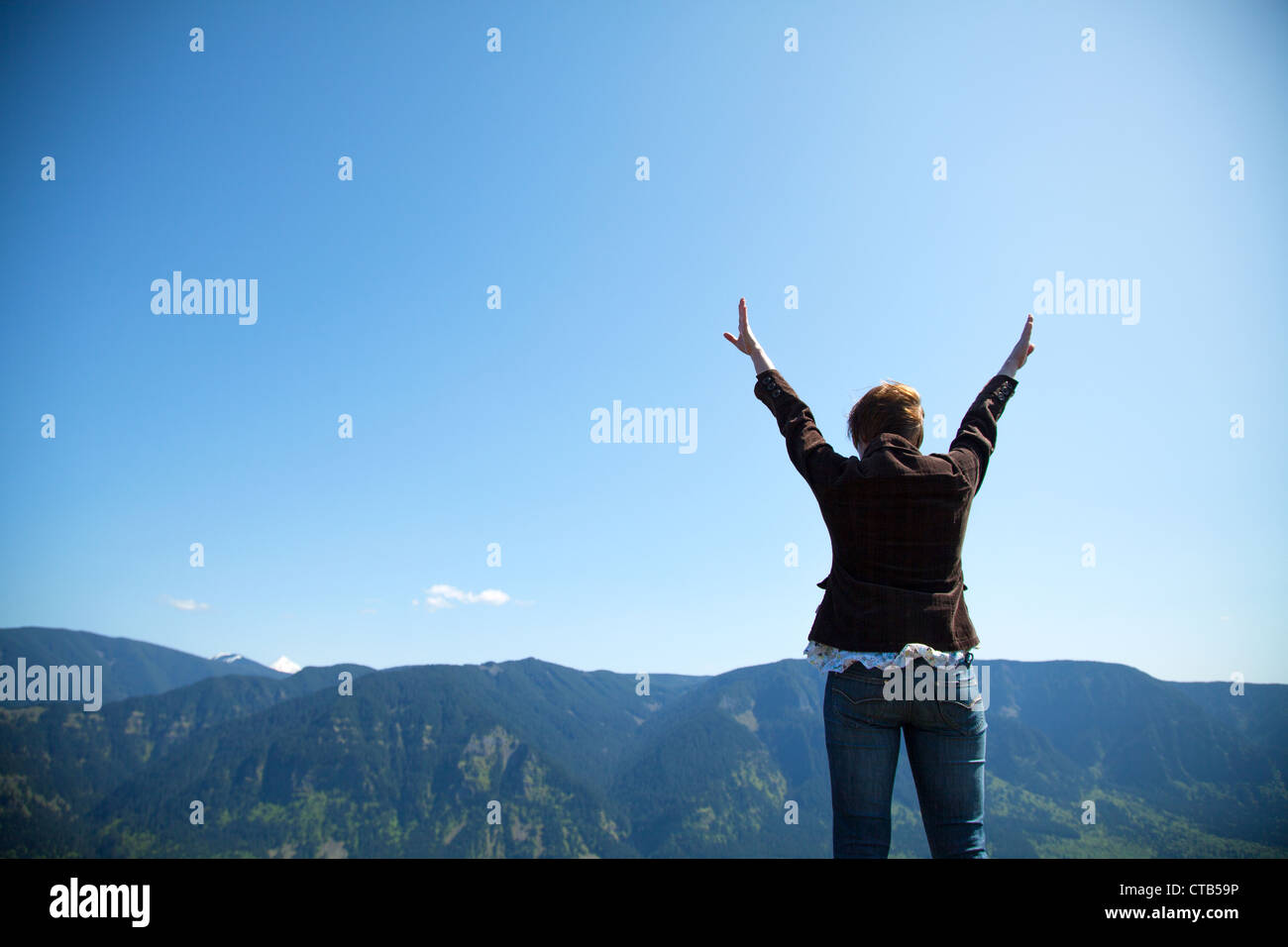 Woman with raised hands against blue sky Stock Photo - Alamy