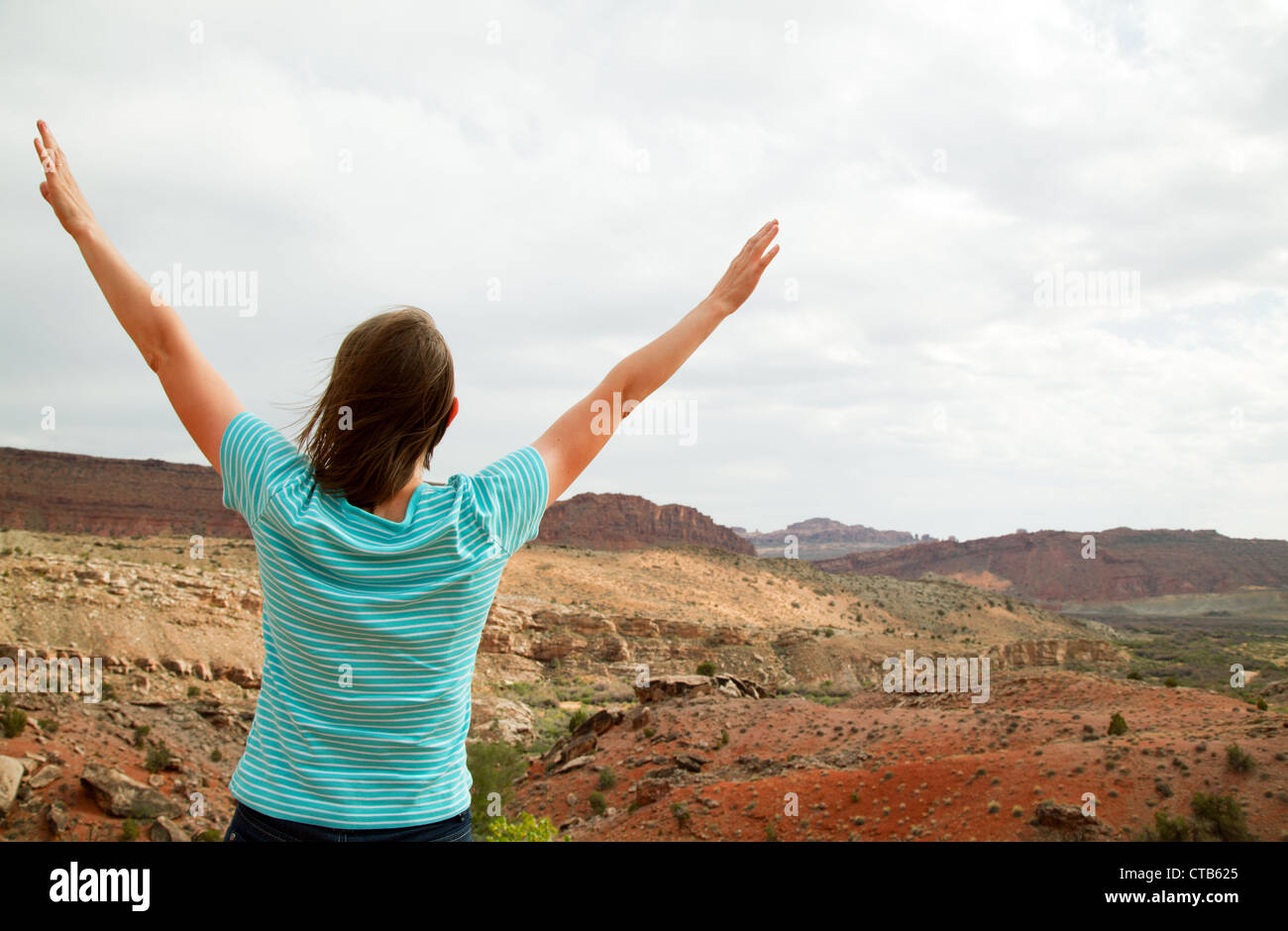 Woman with raised hands against cloudy sky Stock Photo - Alamy