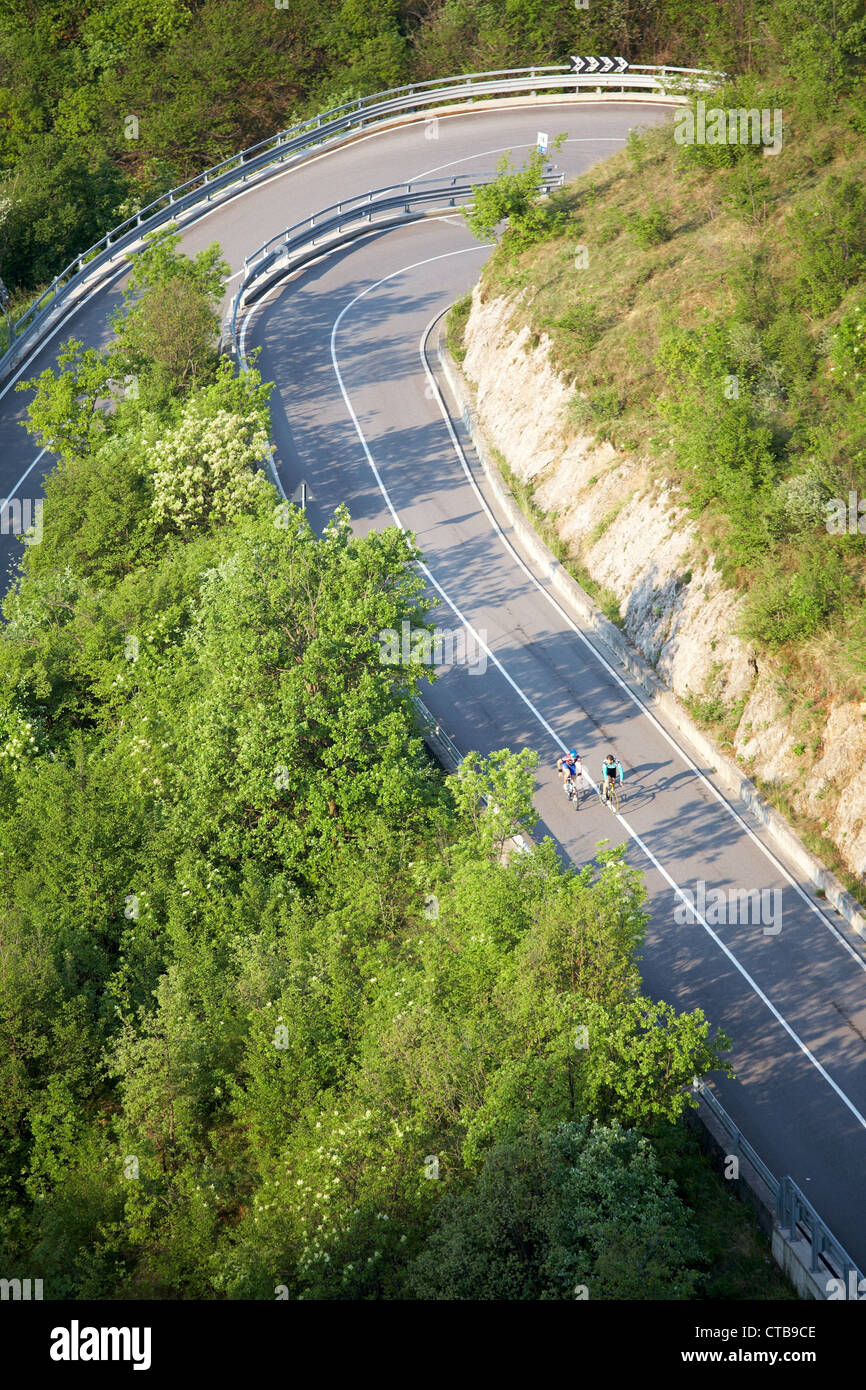 Steep road with serpentines with cyclist, Italy Stock Photo