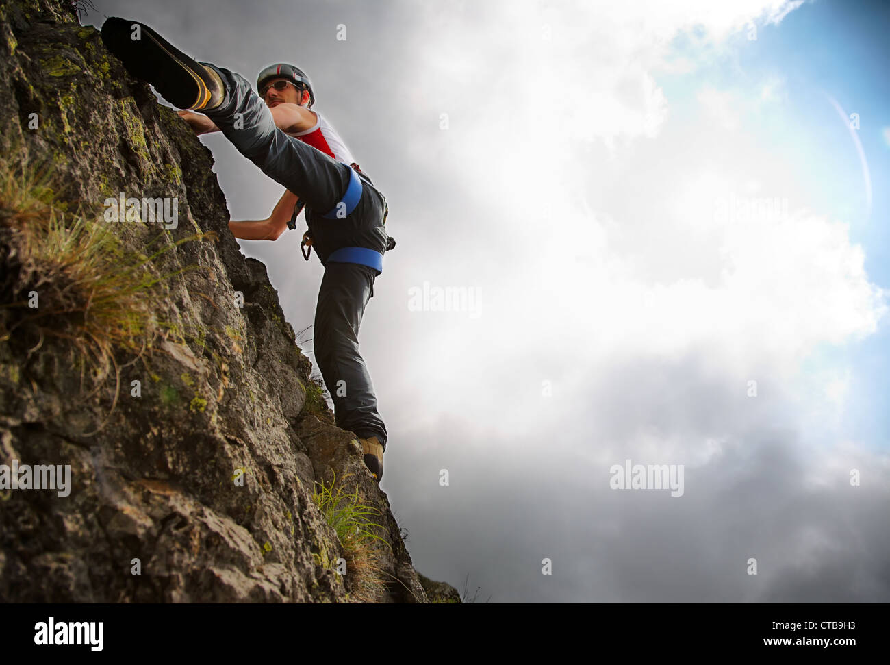 White young male rock-climber summer season upward view horizonzal frame vibrant colours back-light copy-space on right Stock Photo