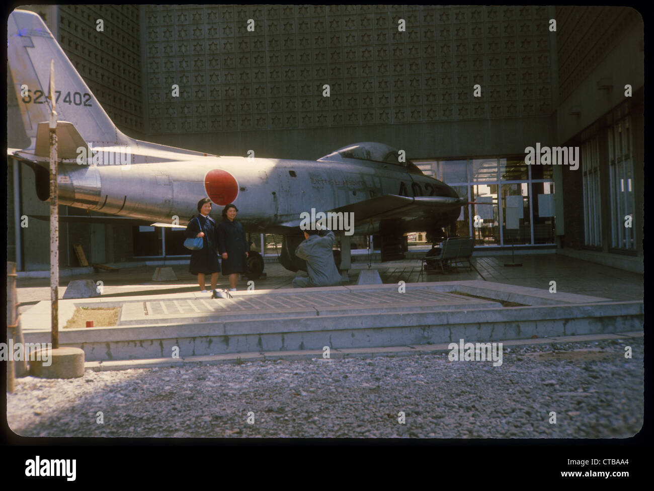 two women standing next to jet with japanese markings Japan color 1960s Stock Photo