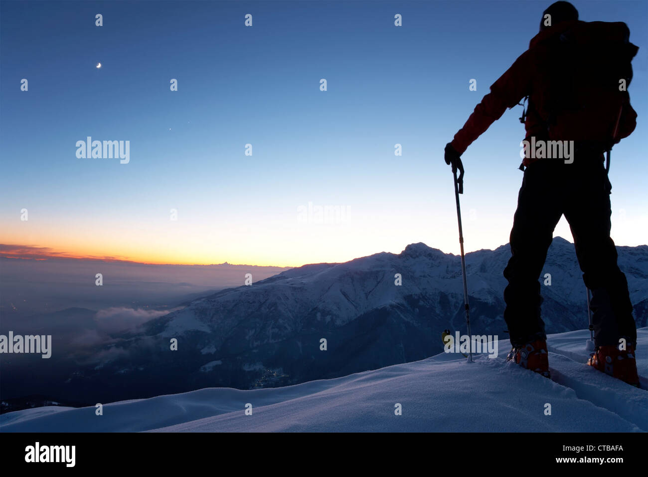 At dusk brave backcountry skier reaching summit mountain after long day walking in wilderness Adventure exploration concept Stock Photo