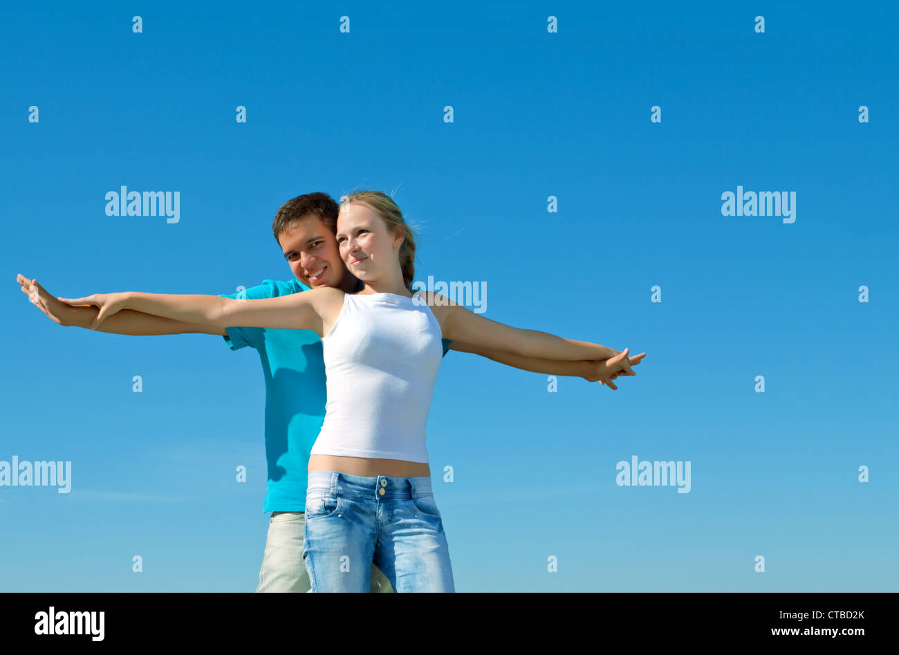 young beautiful couple embracing against blue sky Stock Photo - Alamy