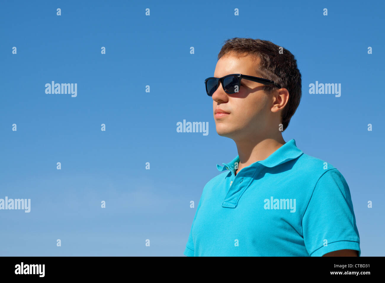 young serious man in sunglasses against blue sky Stock Photo - Alamy