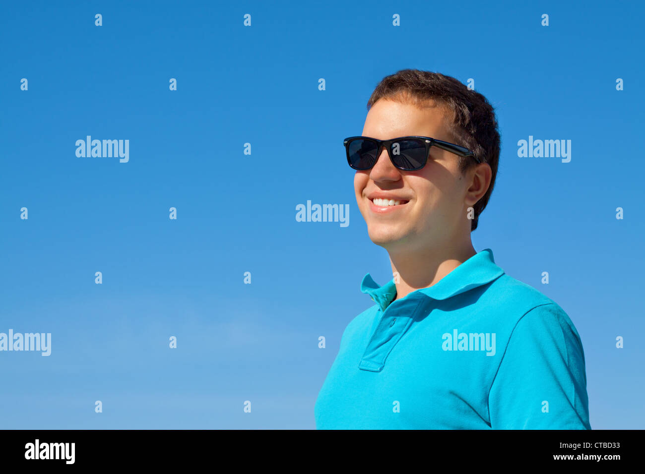 young cheerful man in sunglasses against blue sky Stock Photo - Alamy