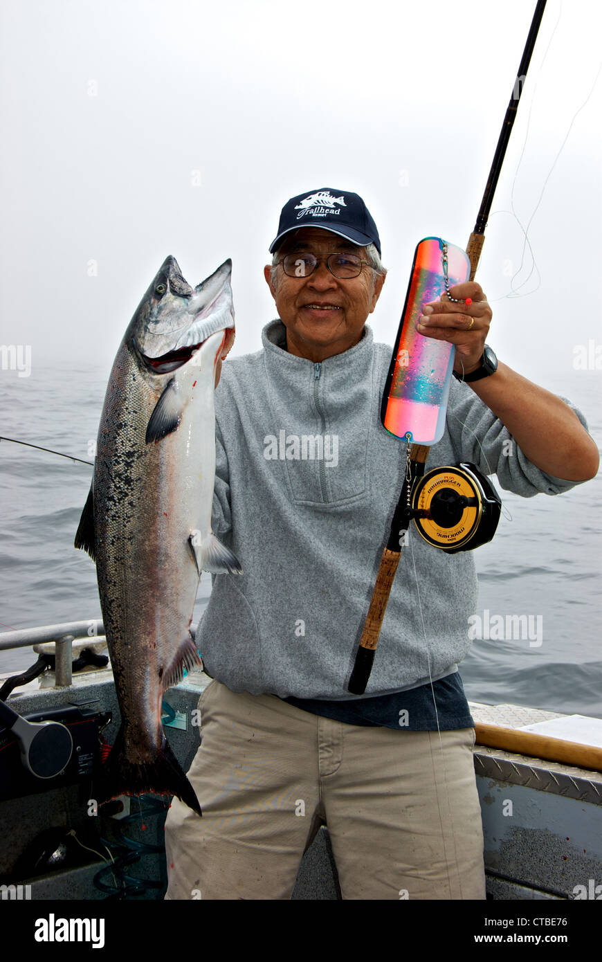 Asian sport fishing angler holding 20-pound chinook salmon rod