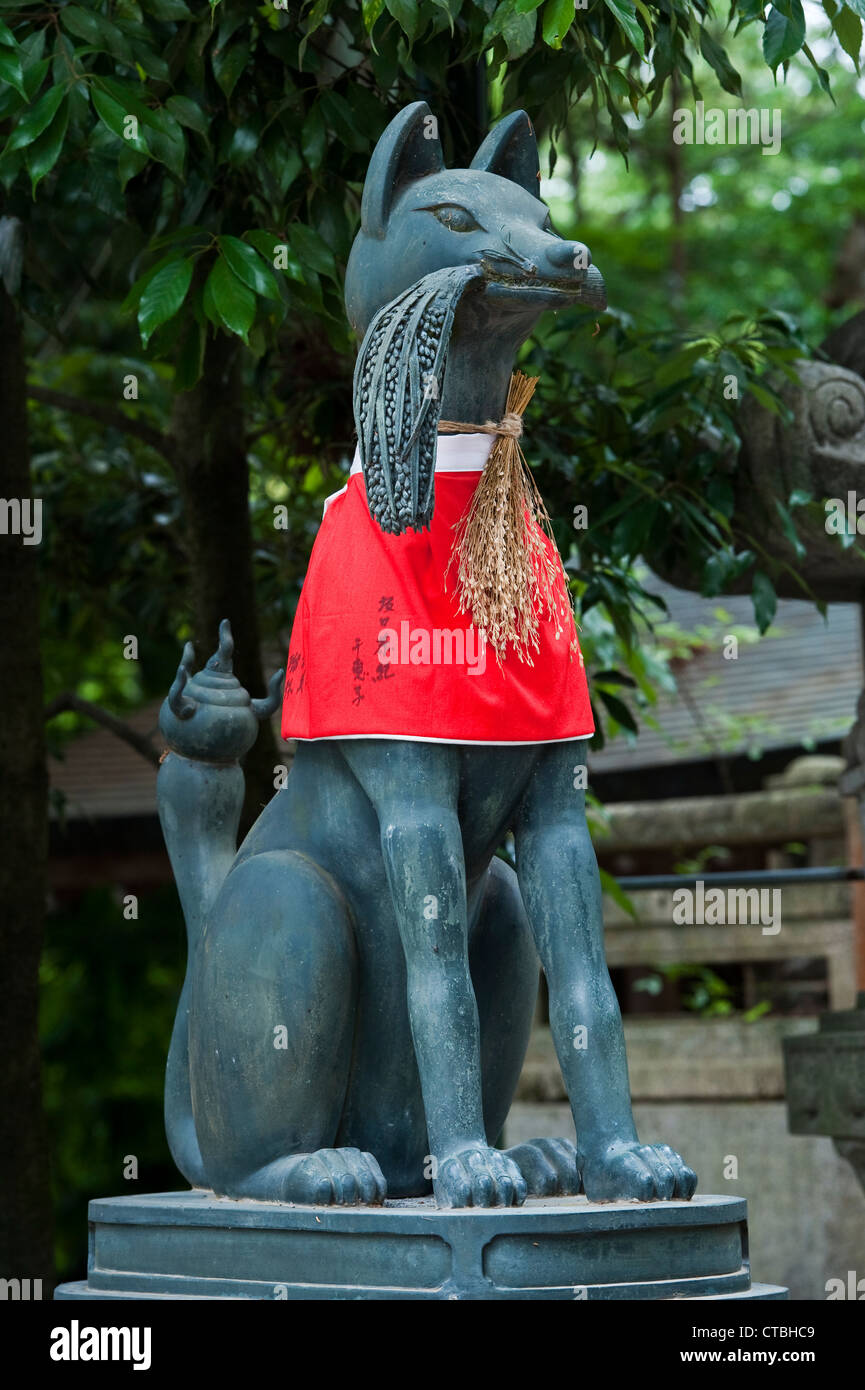 A statue of a kitsune (fox spirit) with newly harvested rice around its