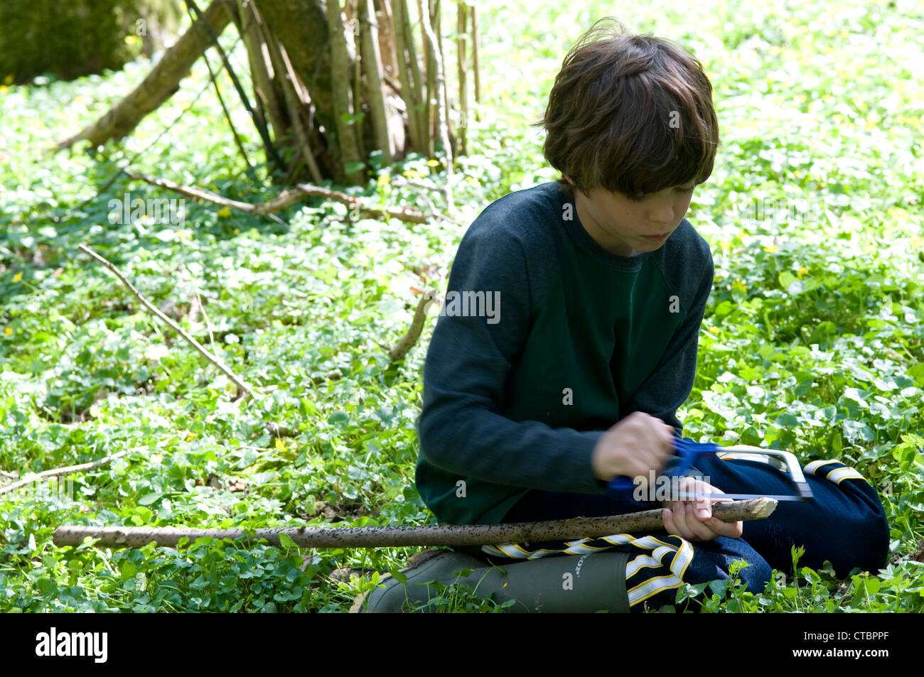 Boy learning how to saw wood outdoors Stock Photo Alamy