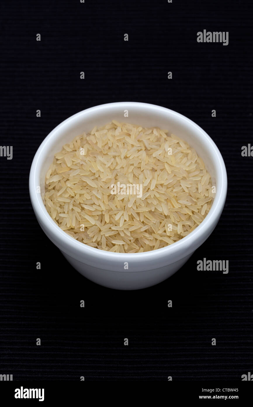 Long grain rice in a white dish black background Stock Photo