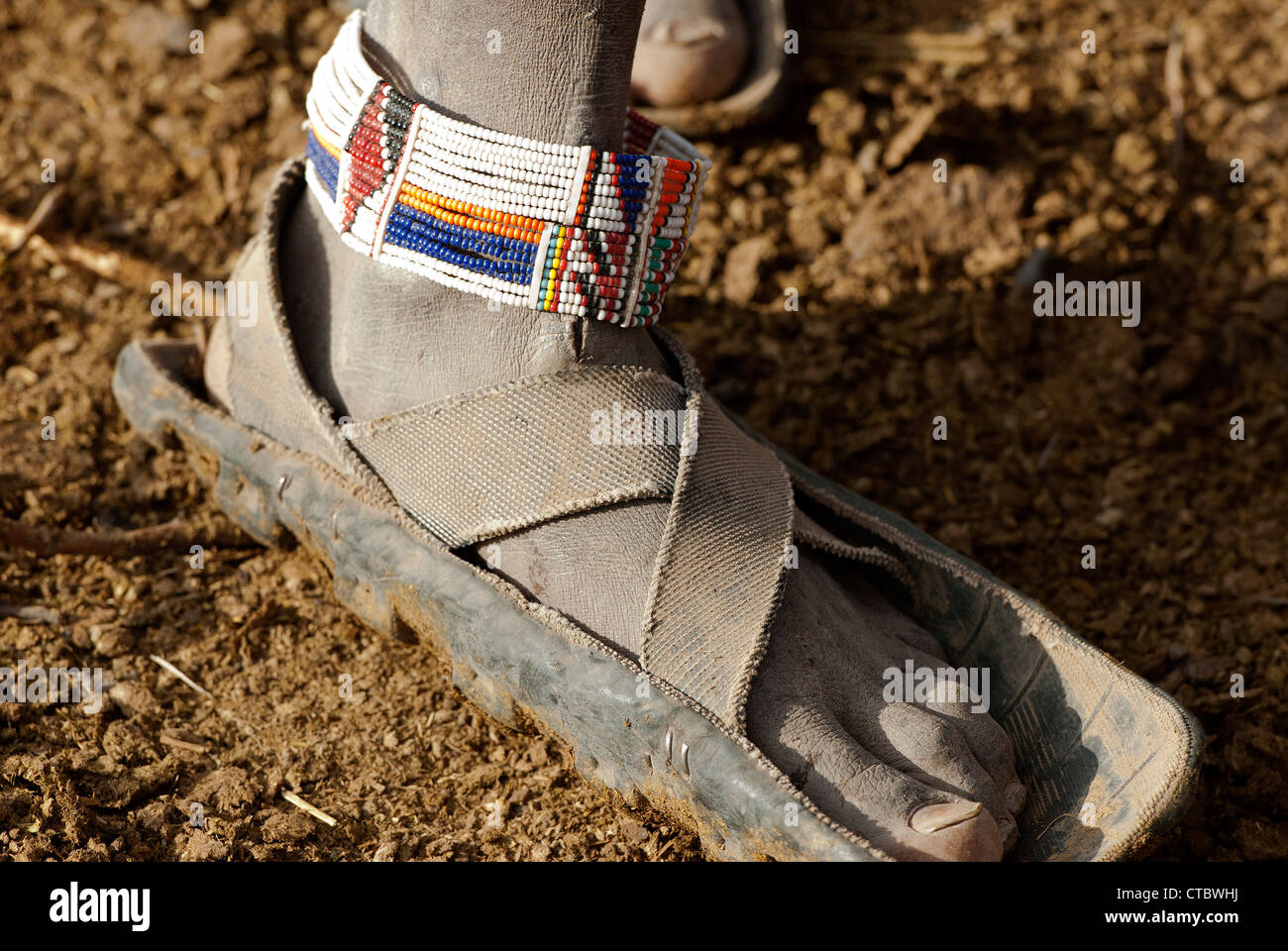 The dry, dusty feet of a Maasai Tribesman with beaded adornment Stock Photo