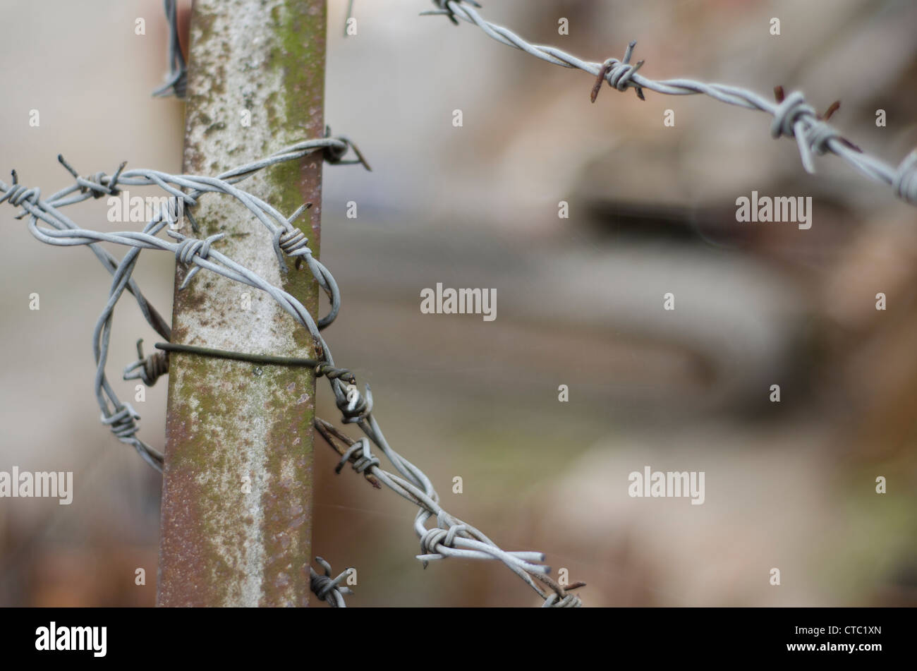 Closeup of barbed wire wrapped around a metal bar with industrial