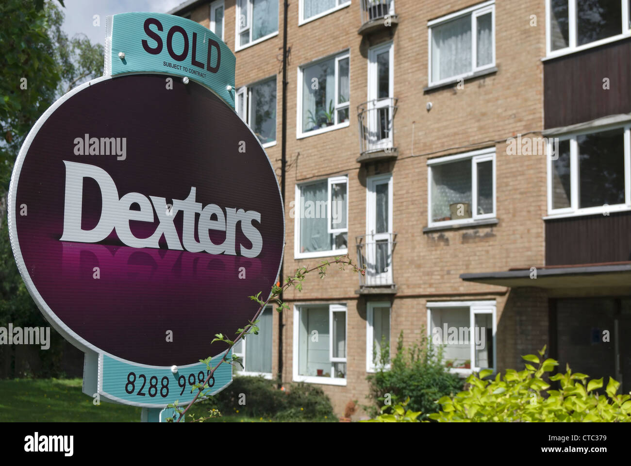 dexters estate agent's sold sign adjacent to a block of flats in richmond upon thames, surrey
