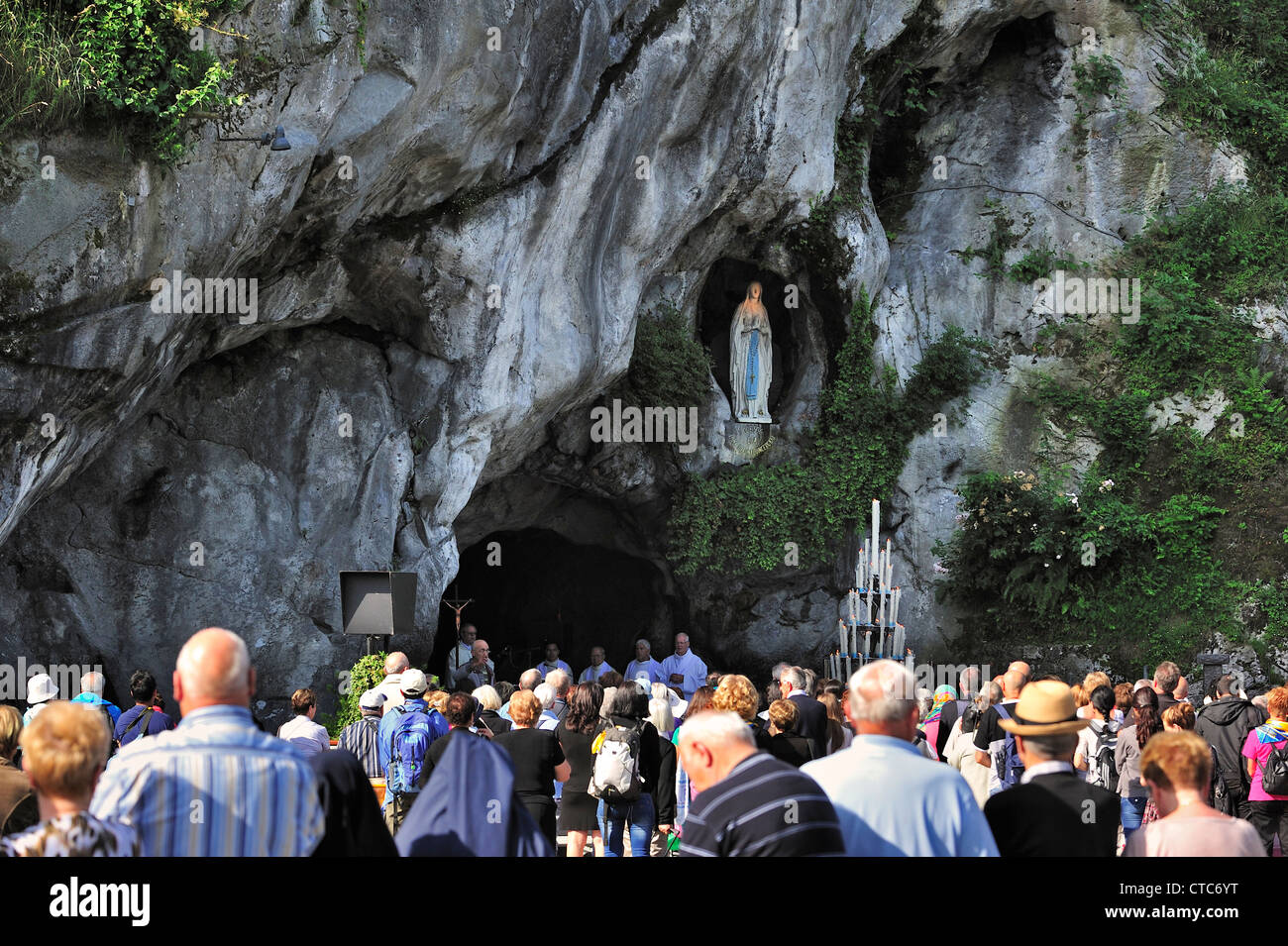 Pilgrims praying in front of the grotto at the Sanctuary of Our Lady of Lourdes, Pyrenees, France Stock Photo