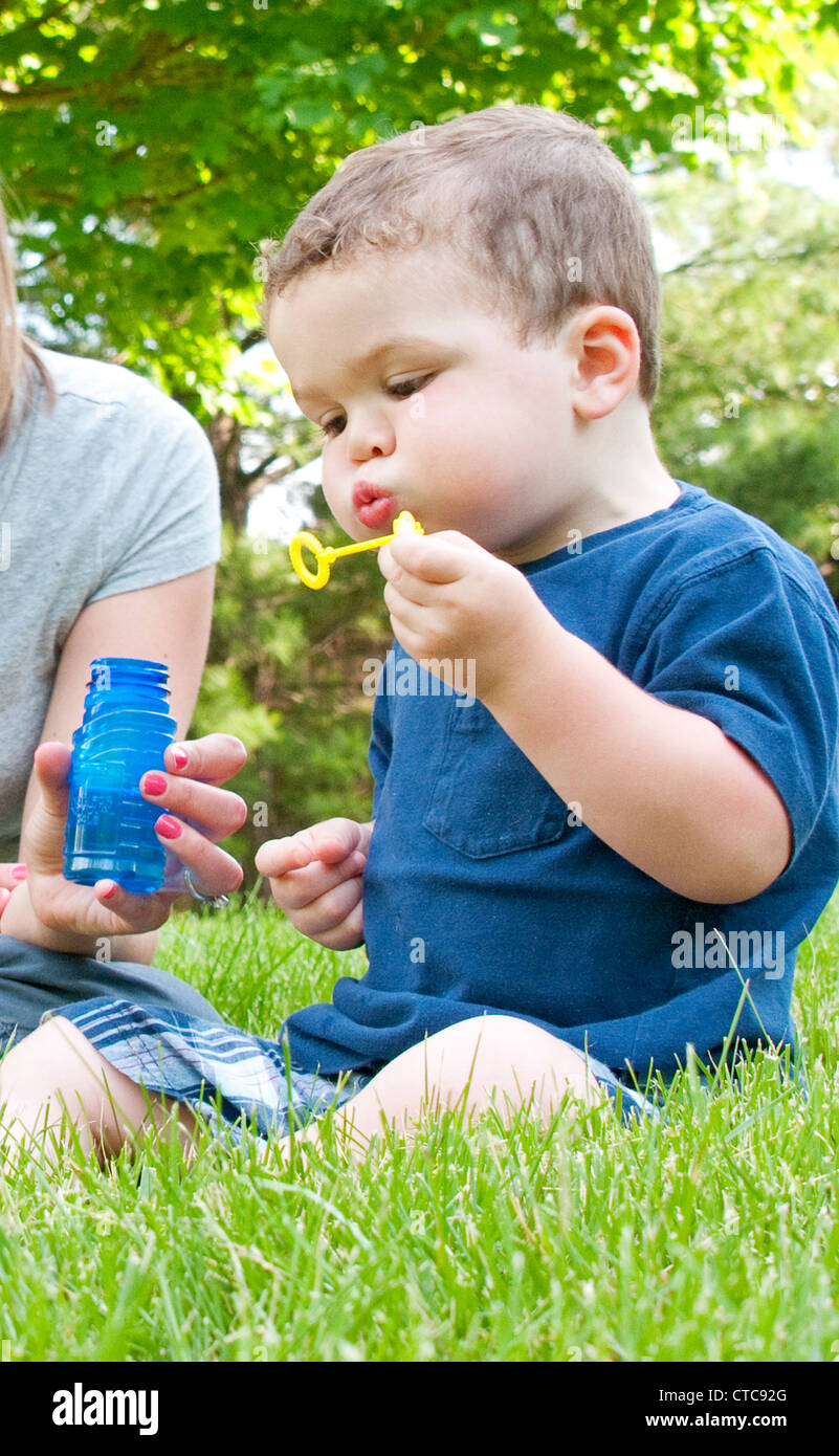 2 and a half year old boy learning to blow bubbles with his mom