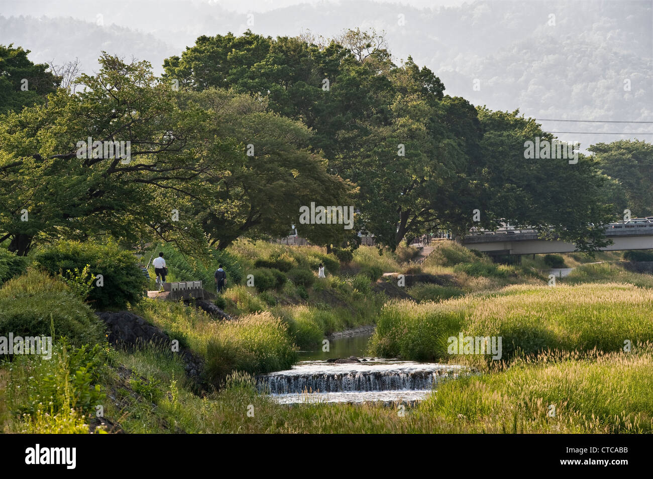 The quiet path along the banks of the Kamo River in Kyoto, Japan, a popular and peaceful place to walk, cycle or picnic Stock Photo