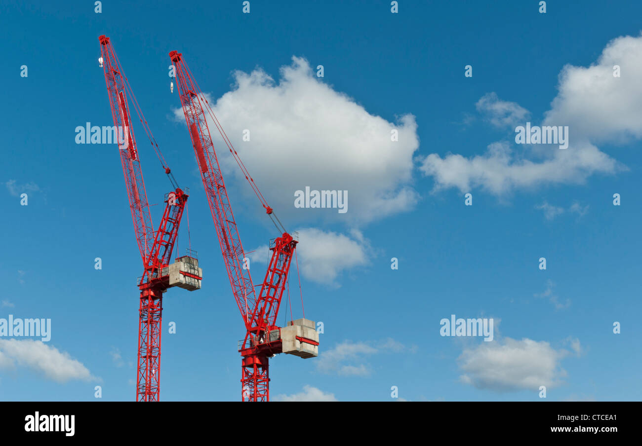 Construction cranes against a blue sky with clouds.  (All logos removed) Stock Photo