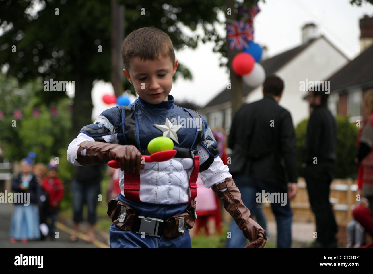 Boy  Egg and Spoon Race At A Street Party Wearing Captain America Fancy Dress During Queen's Diamond Jubilee Surrey England Stock Photo