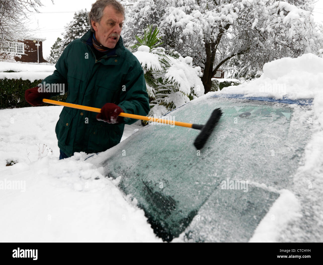 Man Using A Rubber Wonder Broom To Clear The Ice And Snow Off A Car