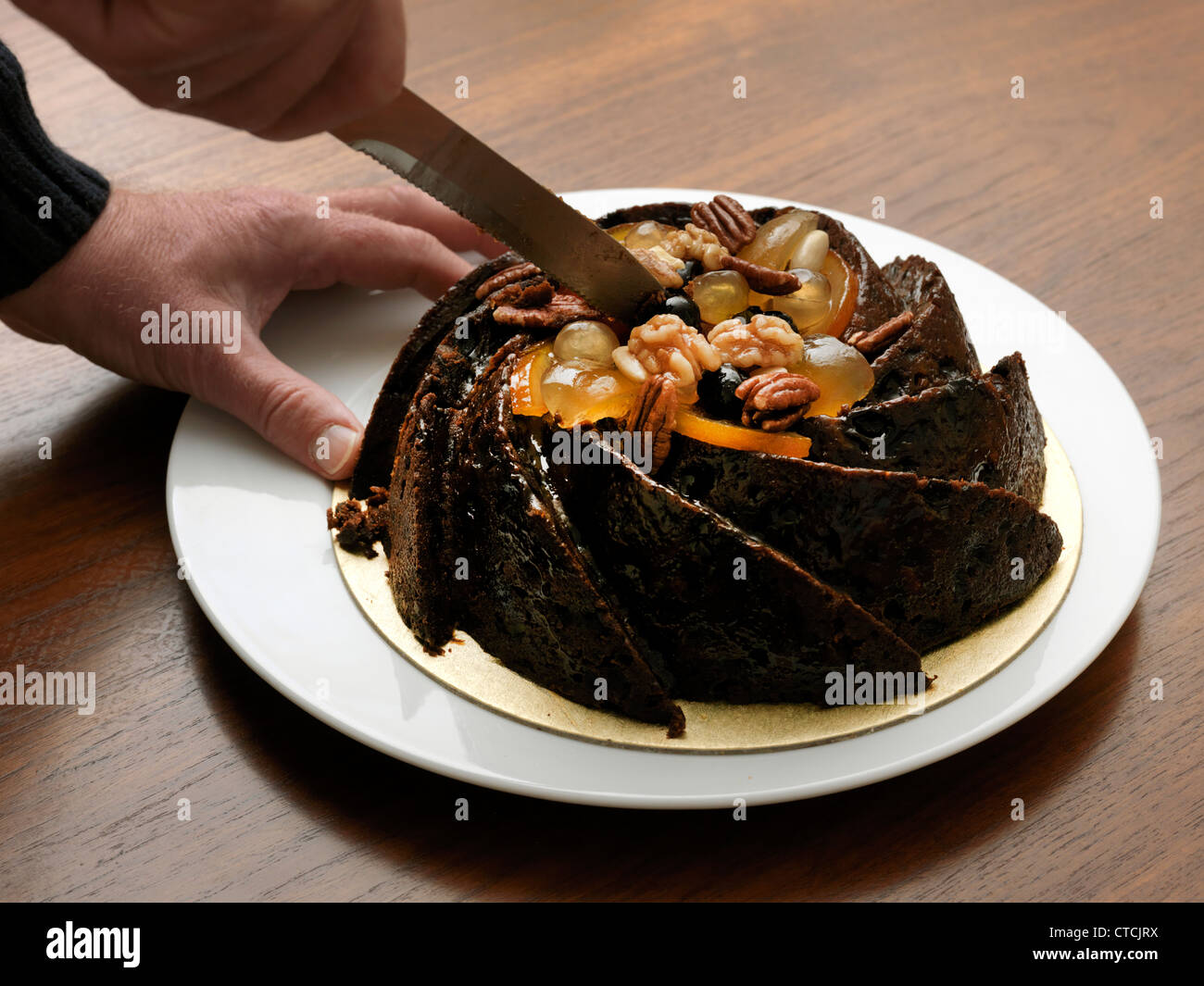 Hands Cutting Christmas Fruit Cake With Walnuts Stock Photo